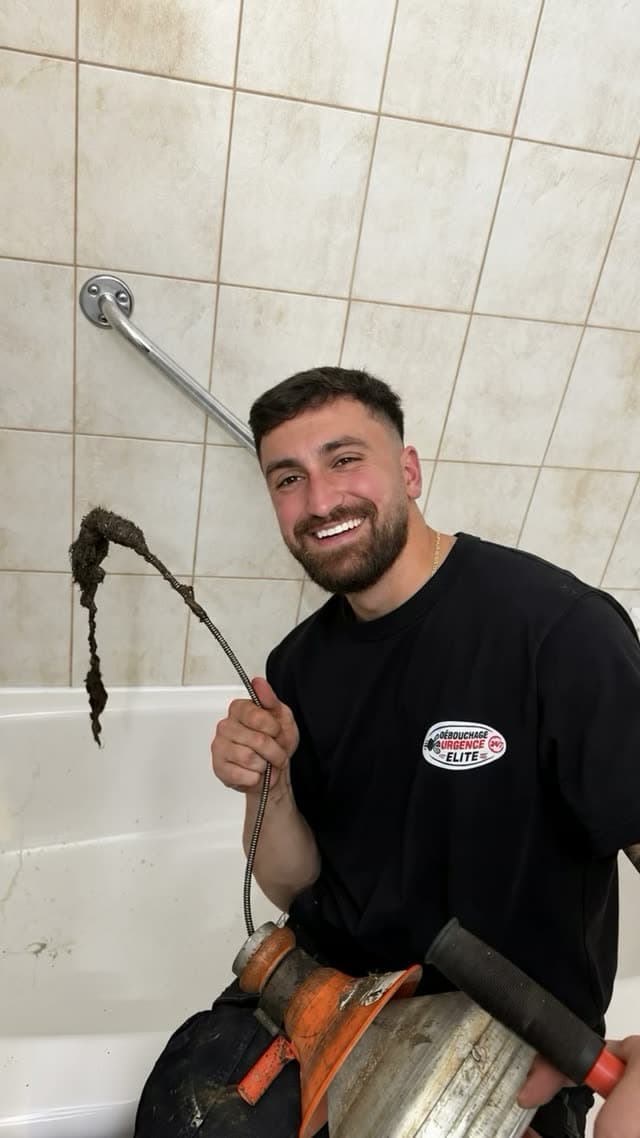 Technician pulling a hair clog out of a bathtub drain